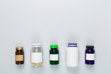 Plastic bottles with vitamins on color background, top view
