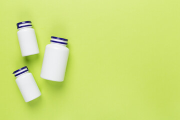 Plastic bottles with vitamins on color background, top view