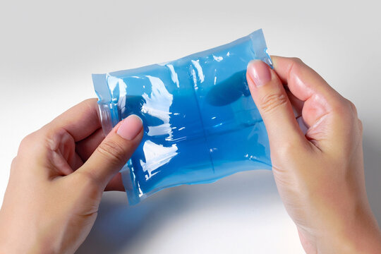 Hands holding blue color cold gel pack on white background