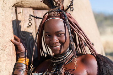 Happy Himba woman smiling, dressed in traditional style at her village in Namibia, Africa. - 614844326