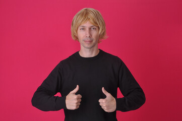 homem com peruca loira engraçada apontando para anúncio ou promoção em fundo rosa 