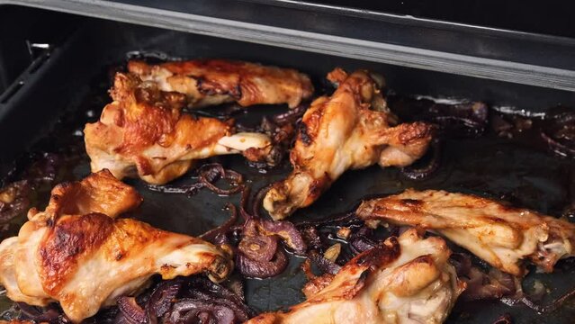 Girl hand take out turkey wings and legs with onion from oven. Ready hot bird meat barbeque