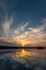 Scenic sunset with cirrus clouds over a river or lake with calm water