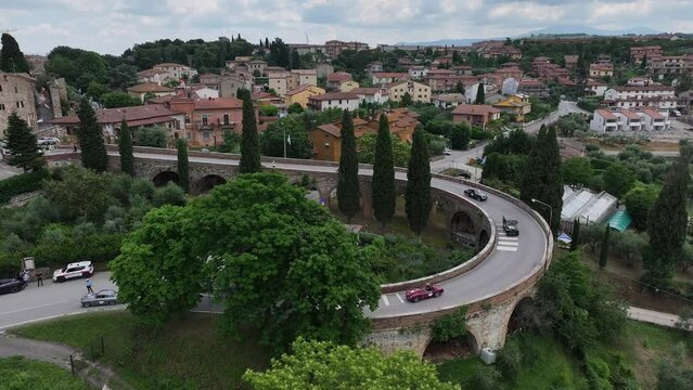 Auto d'epoca sul ponte storico di San Quirico D&rsquo;Orcia in Toscana.
Vista aerea della citt&agrave; e delle auto storiche.