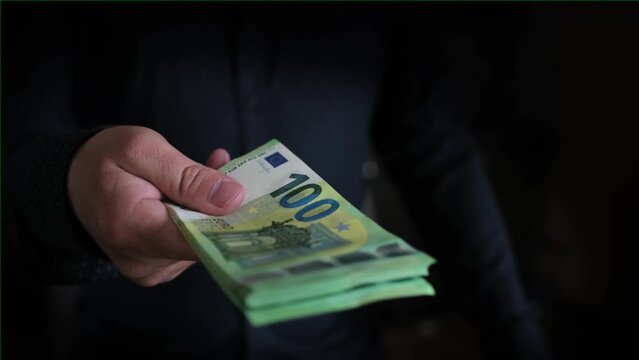Man holds out euro cash to pay for the purchase. Man giving money, close up, black vignette. Financial business concept. Close up man's hand gives one hundred money euro.