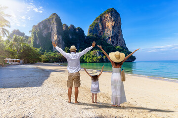 A happy family stands on the beautiful beach of Railay, Krabi, Thailand, during their summer...