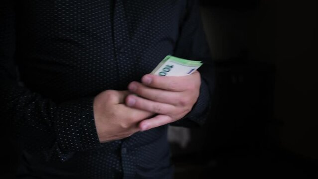 Male holds pack of 100 euro bills on a dark background close-up. Bribery and corruption concepts. Financial business concept.