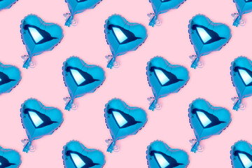 Repetitive pattern made of blue inflatable balloons in a heart shape. Creative concept on a pink background.