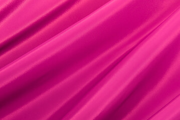 Texture of a smooth luxurious, elegant fabric in pink, purple, red. Purple satin or silk fabric with folds and waves