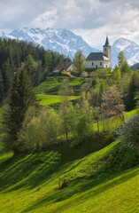 Fototapeta na wymiar Slovenian mountain landscape and cute small church on the hill. St Spirit ( Sveti Duh) church and Kamnik-Savinja Alps in background, Slovenia, Europe