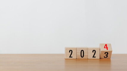Wooded cube block flipping from 2023 to 2024 text on wooden table with white background. New year goal, action plan, business plan, finance and marketing strategy concept.