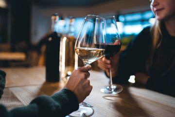 two person cheering and celebrate and drink red and white wine in restaurant