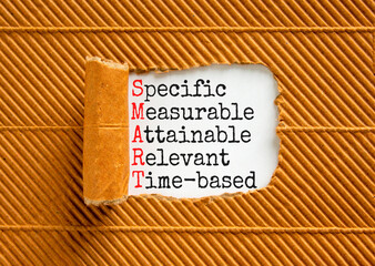 SMART symbol. Concept words SMART specific measurable attainable relevant time-based on paper. Beautiful brown background. Business SMART specific measurable attainable relevant time-based concept.