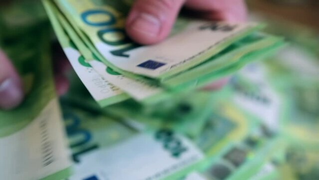 Man quickly rereads pack 100 euros bills and passes it to the woman hands. Concept distribution of the family budget.