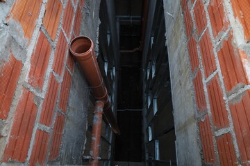 Inicio de una tubería colocada sobre un pared en construcción con un fondo visible