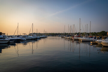 Boats are neatly lined up in a row in the harbour in Port Elgin, Ontario during a late evening sunset.