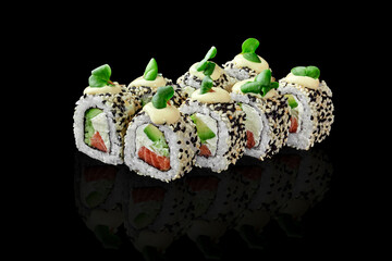 Salmon Philadelphia rolls in sesame topped with mayonnaise and greens on black