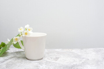 White cup with Jasmine on a marble table, light background