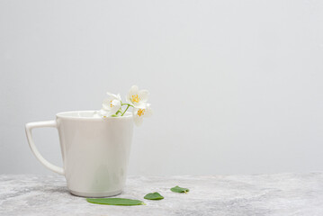 White cup with Jasmine on a marble table, light background