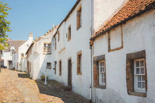 Charming and quaint old town cobblestone lane and white harling cottages in the medieval village of Culross, a popular filming location in Fife, Scotland, UK.