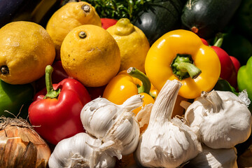 Organic vegetables garlic heads, yellow and red paprika, onions, lemons close-up. Summer and autumn garden background with a harvest of various vegetables. Ingredients for Mediterranean diet.