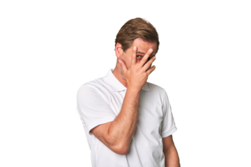 A middle-aged man isolated blink at the camera through fingers, embarrassed covering face.