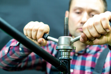 A bicycle mechanic on a black background holds in his hand a professional tool. An old black...