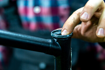 Bicycle repair. Black bicycle frame on a black background in the workshop. Replacement of bicycle steering column cups.