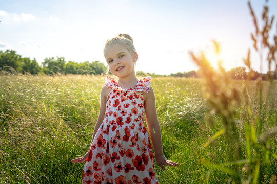 little toddler girl having fun in the meadow at sunset