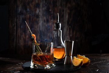 Cognac and spices in a glass. Bartending still life with dark light. A beam of light on a glass.