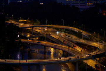 Obraz premium Night photo of a glowing multi-level road junction with heavy traffic. Roads in the metropolis