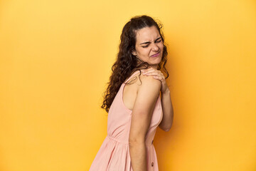 Fototapeta premium Young Caucasian woman, yellow studio background, having a shoulder pain.