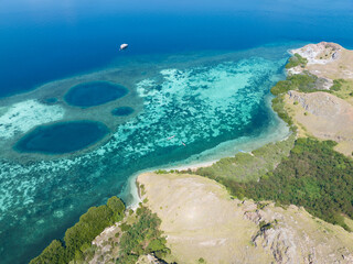 Shallow blue holes are found on a shallow reef flat near the island of Komodo, Indonesia. Blue holes can be caused in different ways but are often collapsed limestone caves.