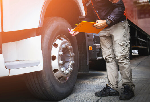 Auto Mechanic is Checking the Truck's Safety Maintenance Checklist. Lorry Driver. Inspection Truck Safety of Semi Truck Wheels Tires.