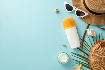 Prepare for a day in the sun with these essentials on a pastel blue background. Top view of unmarked sunblock lotion and SPF cream jar, sunglasses, a headwear,rattan bag, shells, starfishes, palm leaf