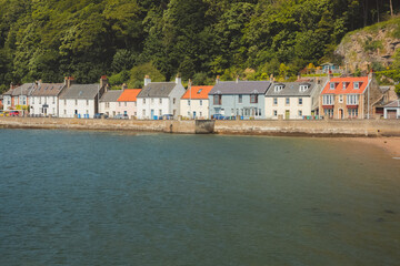 Fototapeta premium A colourful row of waterfront homes on a sunny summer day at the coastal seaside village of Limekilns, Fife, Scotland, UK.