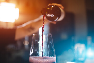 bartender pouring red luxury wine in wineglass, closeup macro