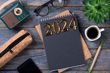 New year goals 2024 on desk. 2024 goals list with notebook, coffee cup, plant on wooden table. Resolutions, plan, goals, action, checklist, idea concept. New Year 2024 resolutions, copy space