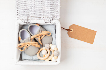 Obraz na płótnie Canvas Gift basket with gender neutral baby garment and accessories. Care box of organic newborn booties, fashion, branding, small business idea. Flat lay, top view