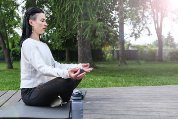 A young beautiful woman does yoga and meditates in the city park. The concept of sports and active life.