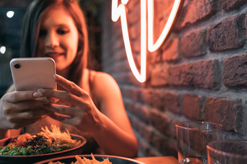 Young girl chatting on her mobile phone while enjoying her poke bowl. Focus on the telephone.