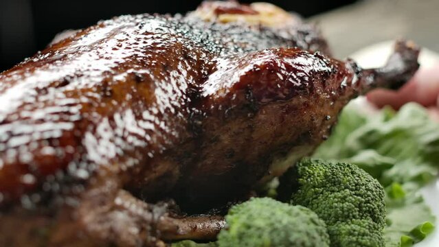 Close-up of the roasted juicy duck on the plate full vegetables placed on table