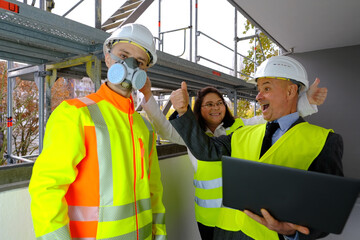 Two men, an architect and construction engineer, foreman and one woman inspect the performance of a project on a laptop, a construction site of a multi-storey house, building in progress