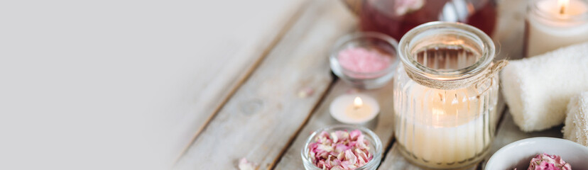 Aromatherapy. Bath salt, pure natural essential oils, floral rose extract. Spa treatment, skin care, relaxation with burning candles, herbal organic hot tea. Towel, wooden background banner copy space