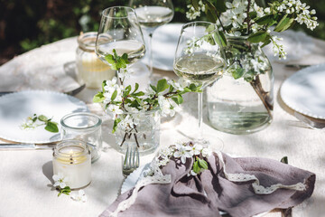 Rustic elegant eco friendly zero waste trendy wedding reception table decor with fresh spring apple cherry flowers in bloom. Beautiful marriage decoration, holiday event outdoors in the family garden