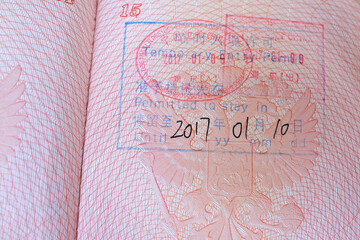 close up part of pages of foreign passport with foreign visas, border stamps, permits to enter...