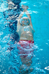 Swimmer boy swims backstroke swimming style in the pool - 614897795