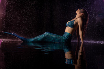 Mermaid in water with purple and blue lights duiring rain