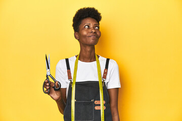 African tailor with scissors and measuring tape, fashion concept dreaming of achieving goals and purposes