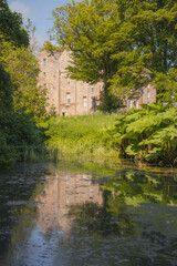 Fototapeta na wymiar The historic Kellie Castle and gardens reflected in a pond on a sunny summer day in East Neuk, Fife, Scotland, UK.